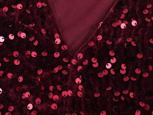 Detailed macro view of burgundy velvet fabric texture and shiny sequin embellishments