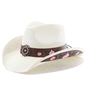 Detail of white western cowboy hat featuring floral embroidery and pink gemstone buckle