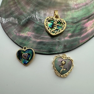 Close-up of 18K gold-plated heart charms with shell inlays and floral patterns