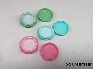 Close-up of 5g macaron plastic cream jars in green blue and pink with screw caps
