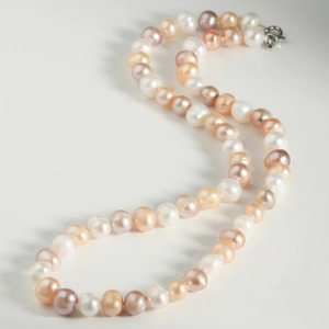 Detailed view of multi-color freshwater pearls with a silver lobster clasp on white background