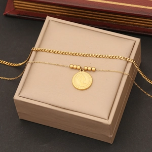 Close-up of golden coin necklace with Elizabeth II pendant on a brown jewelry box