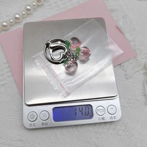 Detail shot of a peach-shaped keychain on a digital scale showing its weight in grams