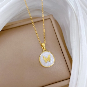 Macro detail of gold-plated butterfly pendant with white inlay on satin background