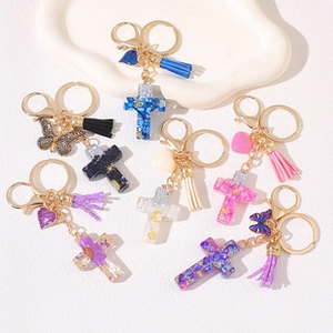 Detailed close-up of resin cross keychains with glitter, gold hardware and colorful tassels