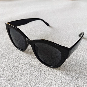 Classic black cat-eye sunglasses with glossy frame shown in a 45-degree top-down view