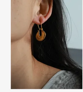Detail of vintage horseshoe gold hoop earrings with beaded texture on model ear