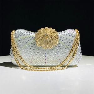Close-up of sparkling rhinestone evening bag with gold floral clasp and chain strap