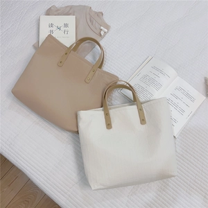 Macro view of minimalist tote bags with pleated fabric texture and leather handles