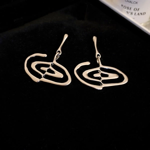 Detailed close-up of silver abstract spiral earrings on a black velvet background