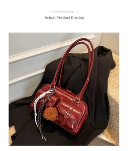 Detailed shot of dark red patent leather hobo bag with front pockets and teddy charm