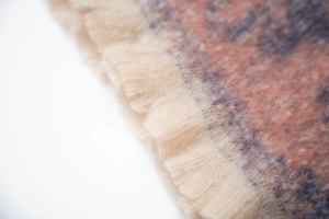 Macro shot of soft jacquard weave texture and fringed edges on floral winter scarf