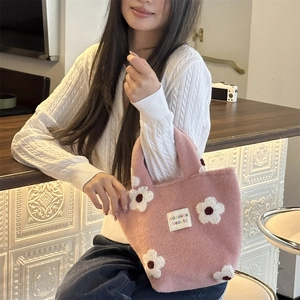 Close-up of pink plush handbag with white 3D floral appliques and branded fabric label