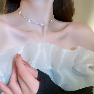 Close-up of a silver butterfly necklace with sparkling rhinestones worn by a model