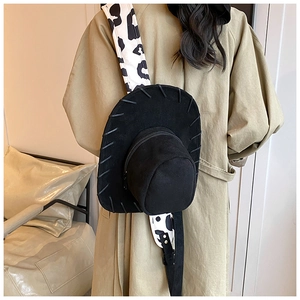 Close-up of black cowboy hat backpack with cow print strap on female model shoulder