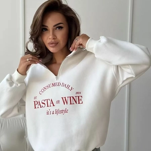 Detail eines weißen Sweatshirts mit halbem Reißverschluss und rotem Buchstabendruck