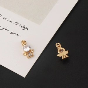 Macro detail of gold-plated angel pendants with cubic zirconia inlay on a white card