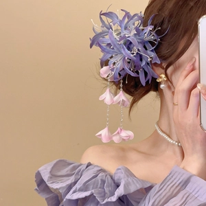 Détail d'une pince à cheveux fleurie en tissu violet avec pompon sur une coiffure