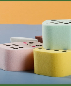 Close-up of colorful makeup sponges with cute cartoon expressions in a stacked display