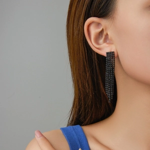 Elegant long black tassel drop earrings with shimmering rhinestones on a female model