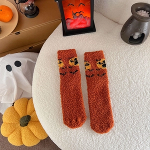 Close-up of orange coral fleece socks with black pumpkin face embroidery for Halloween