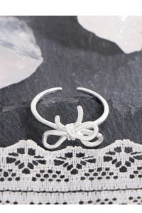 Detailed macro view of S925 sterling silver bow ring on black rock and white lace background
