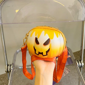Close-up of orange pumpkin handbag with wide printed strap and cartoon face design