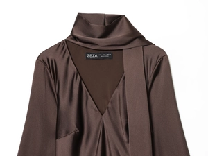 Détail d'une robe en satin marron foncé avec col écharpe et texture soyeuse