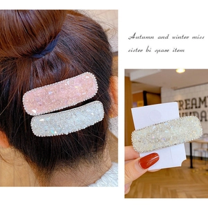 Detailed close-up of two square hair clips with glitter crystals and small rhinestones
