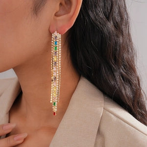 Detail of long tassel earrings with colorful gemstones and gold chain on model