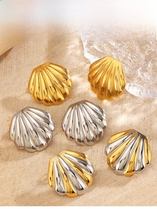 Macro shot of seashell-shaped metal stud earrings in gold and silver on sandy background