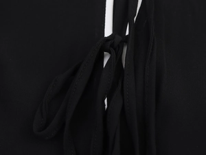 Détail de la bordure blanche contrastée et du nœud noir sur une robe en mousseline
