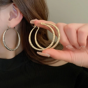 Large textured hoop earrings in gold and silver finish with striped geometric pattern