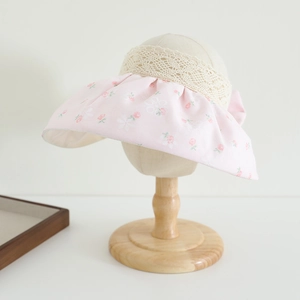 Detail of pink floral sun visor with delicate white lace trim and foldable wide brim