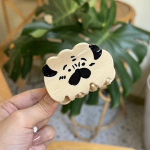 Detailed view of a cute pug-shaped acetate hair claw clip in creamy yellow color