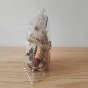 Detail of coffee gnome plush in clear packaging on wooden surface for home decoration