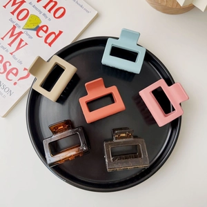 Set of 6 colorful square hollow hair claws in matte pastel shades on a decorative tray