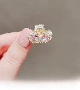 Detail of a gold butterfly hair claw with pink crystals and small white rhinestones