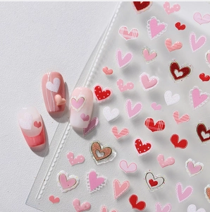 Close-up of heart nail art stickers with 3D embossed designs on pink press-on nails