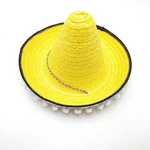 Detailed view of a yellow Mexican straw hat with pom-pom trim and colorful cord.