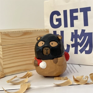 Hand-carved wooden bear figurine with knife-cut texture and red ornament on desk