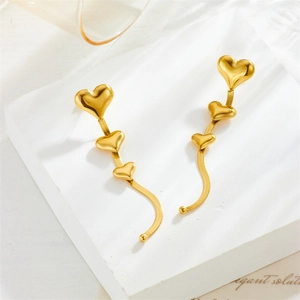 Elegant gold heart tassel earrings with long snake chains on a white pedestal