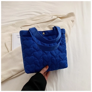 Close-up of blue quilted heart pattern and magnetic buckle on Oxford tote bag