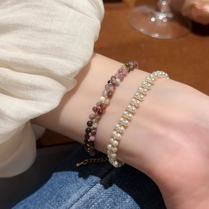 Detailed shot of layered bracelets featuring colorful agate beads and white pearls
