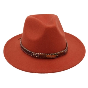 Close-up of brick red wool felt hat with woven band and vintage bronze feather accent