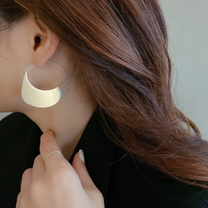 Minimalist silver stainless steel crescent moon earrings worn by a model with brown hair