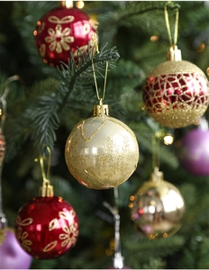 Detailed view of 6cm shiny Christmas balls with glitter patterns on a green festive tree
