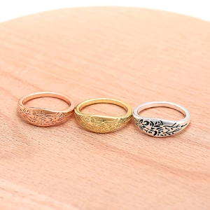 Macro view of three vintage floral rings in rose gold, gold, and silver on a wooden tray