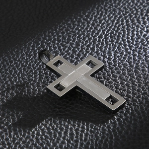 Macro shot of silver layered cross pendant with brushed finish on black leather