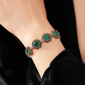 Macro detail of vintage emerald green stone bracelet with bronze floral settings
